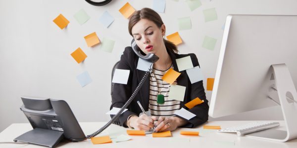 Studio shot of young woman working in office covered with adhesive notes